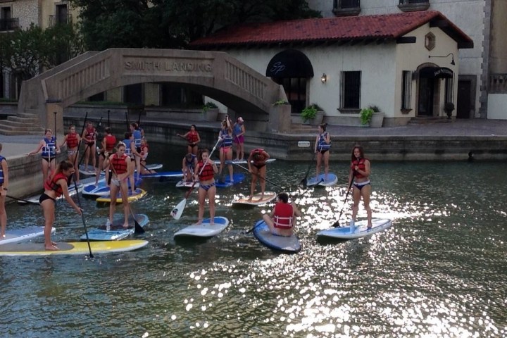 a group of people riding on the back of a boat in the water